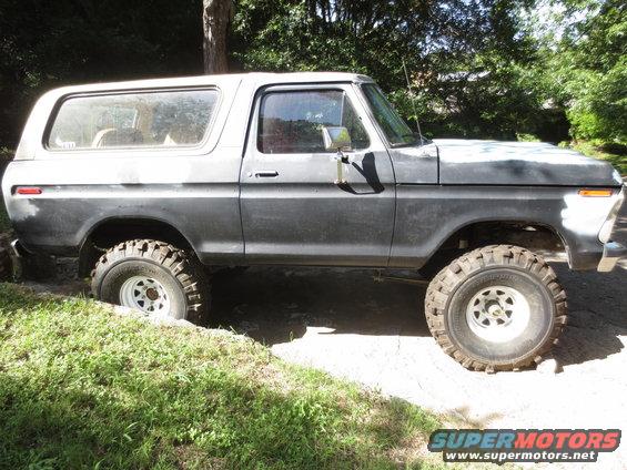Gray 1978 Ford Bronco, side view, lifted with off-road tires, in dirt and grass