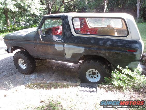 Dark green and white 1978 Ford Bronco with off-road tires, primer patches, and red interior