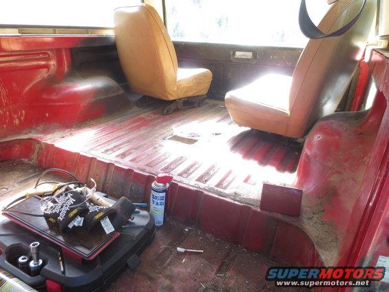 Red vehicle interior with tan seats, tool case, and spray can
