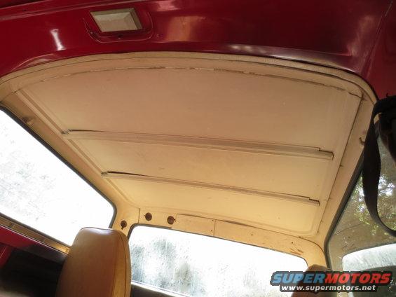 Interior view of a vehicle's headliner and window frame, showing exposed metal and trim