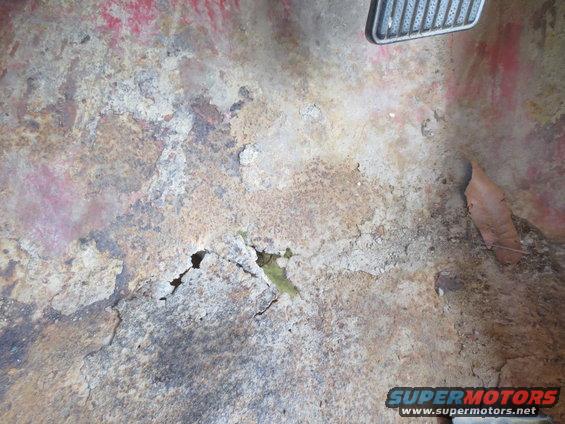 Rusted floor pan with holes and peeling paint