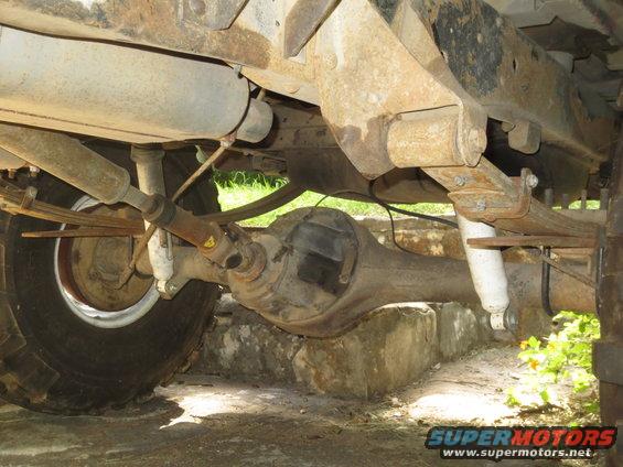 Underside view of a vehicle's rear axle, leaf springs, driveshaft, and exhaust system