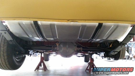 Undercarriage view of a car on jack stands, showing fuel tank and leaf springs