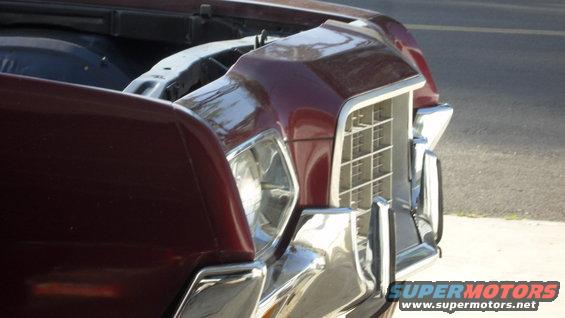 Close-up of a maroon car's front grille and headlight