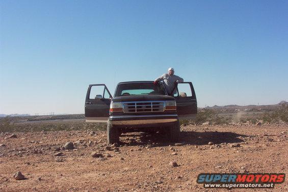 Dark 1992 Ford Bronco with doors open, front view, in a desert landscape