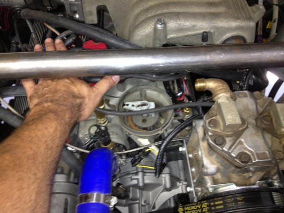 Engine distributor cap and rotor with a hand above, blue hose, and metal tubing