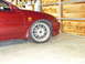 1993 Mazda MX-3 - Close-up of a red car's front wheel and fender, showing a '2.5-V6' badge.