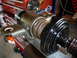 1993 Mazda MX-3 - A metal automotive part, possibly a suspension component, is clamped in a vise in a workshop setting.