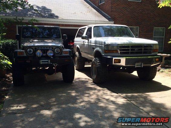 Jeep Wrangler and a lifted 1992 Ford Bronco parked in a driveway