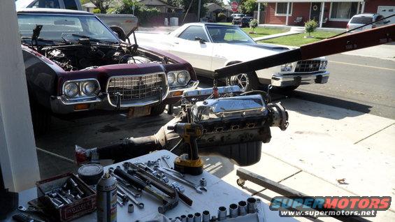 1972 Ford Ranchero with hood open, engine being lifted out by an engine hoist. Tools and parts are on a table