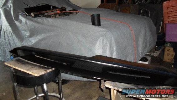 car covered with a gray tarp, with a black part in the foreground