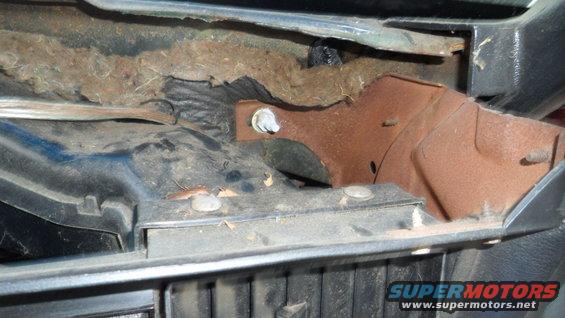 Rusty metal bracket and insulation inside a vehicle's dashboard