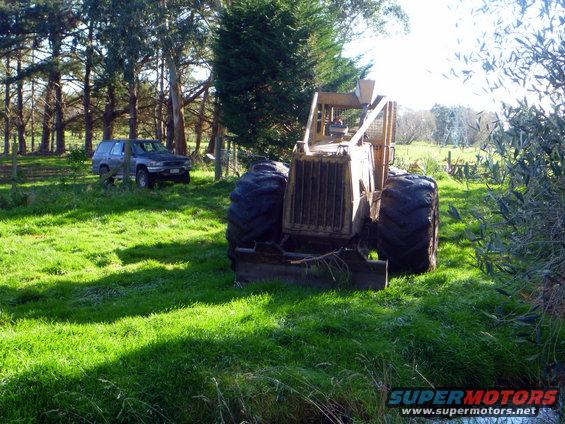 Yellow tractor with large tires in a grassy field