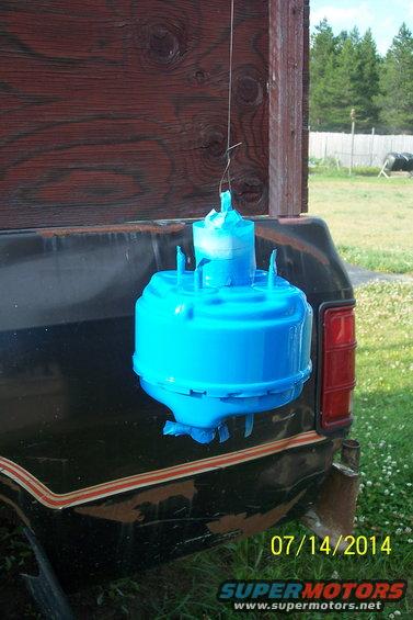Blue brake booster hanging from a wooden surface, with a truck tailgate visible