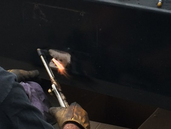Black surface being heated with a torch, showing a repair in progress