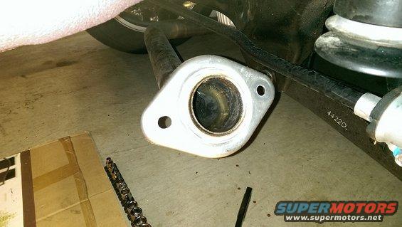 Close-up of an exhaust pipe flange with two bolt holes. Part number 4422D is visible on a nearby component