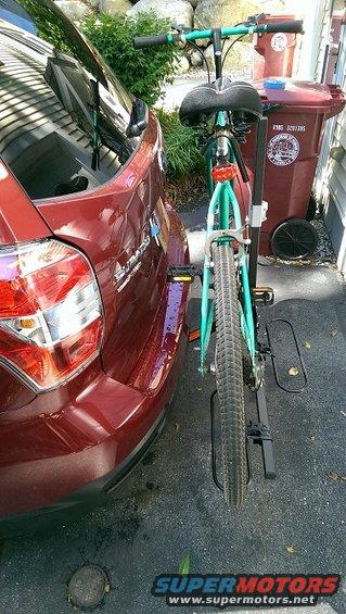 Rear view of a dark red Subaru Forester with a teal bicycle mounted on a hitch rack
