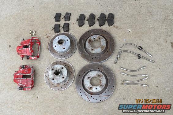 Red brake calipers, rotors, and brake pads laid out on concrete