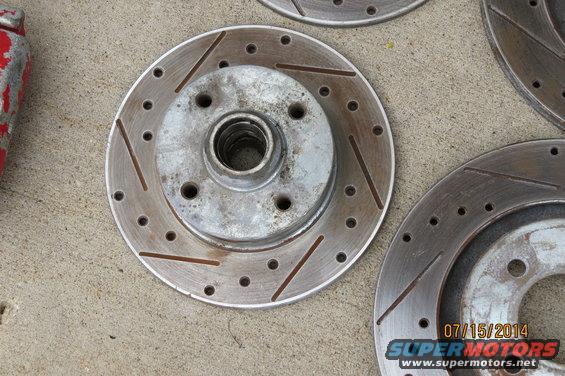 Slotted brake rotor with a red painted caliper fragment on the left