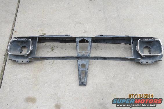 Gray metal front grille support with two square headlight openings and chrome trim