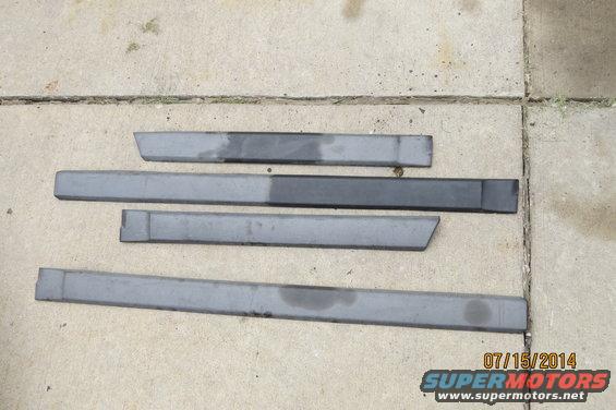 Four gray car door sill trim pieces laid out on concrete