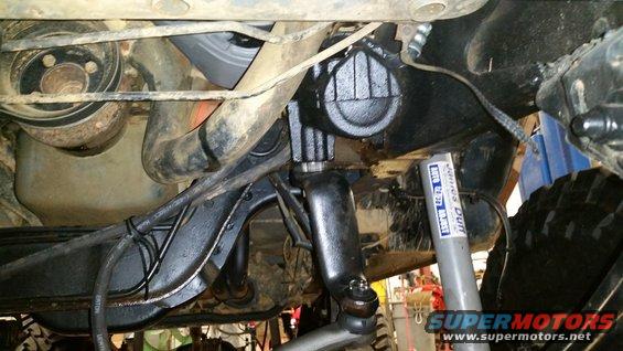 Close-up of vehicle steering linkage and suspension parts, with a shock absorber visible