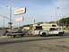 1997 Dodge 3500 - A white Dodge pickup truck tows a boat trailer while carrying a camper shell, parked near a gas station.