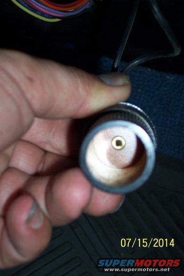 Hand holding a cigarette lighter socket with wires visible in background