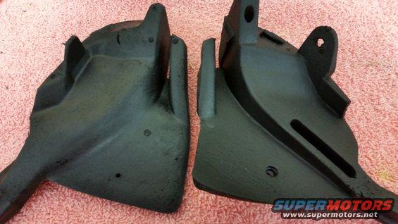 Two black plastic automotive parts on a pink textured surface. One part is on the left, the other on the right
