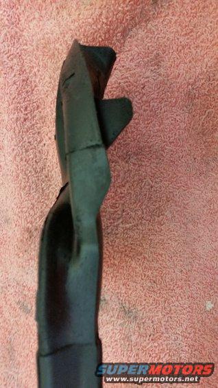 Black plastic car part, possibly a trim piece, resting on a pink textured towel. Watermark reads SUPERMOTORS.NET