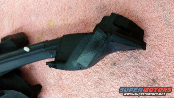 Black plastic trim piece with a white dot on it, lying on a pink textured surface