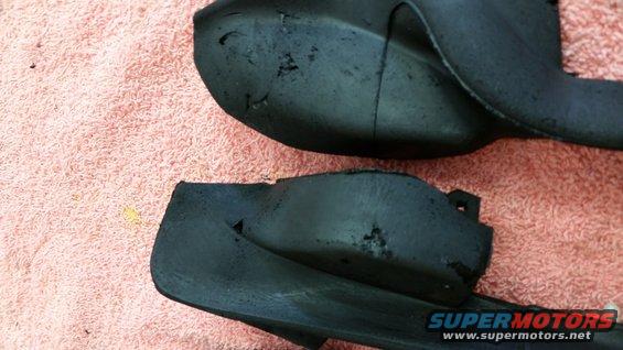Two black plastic car parts with some damage, lying on a pink towel