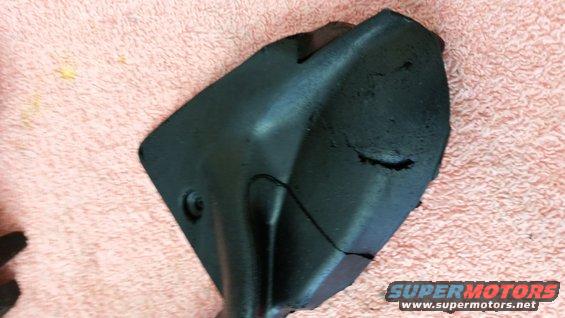 Damaged black plastic automotive part on pink textured surface