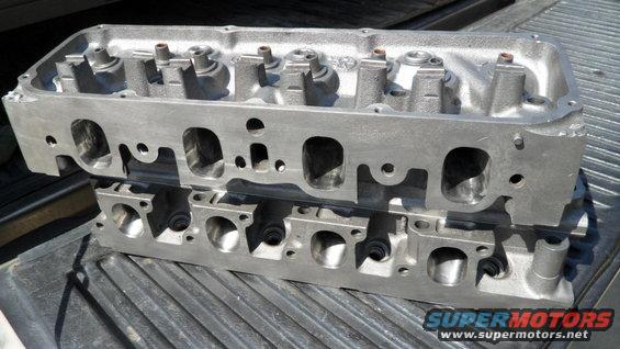 two aluminum engine cylinder heads stacked on a truck bed