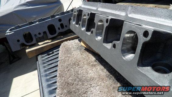 Two gray engine cylinder heads on a truck bed, one in focus