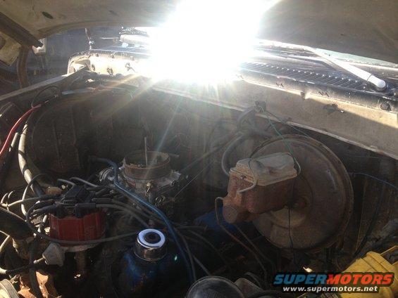 Engine bay of a 1979 Ford Bronco with a V8 engine, carburetor, and brake booster visible