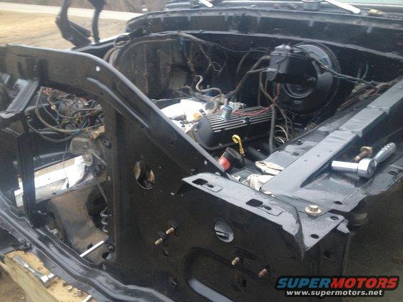 Black vehicle engine bay with exposed engine and wiring