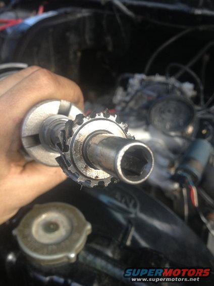 Distributor rotor held in hand, with engine components in background