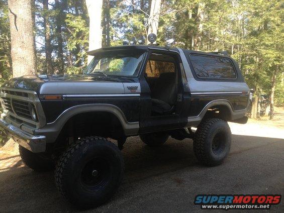 Lifted black and silver Ford Bronco with off-road tires and lights on top