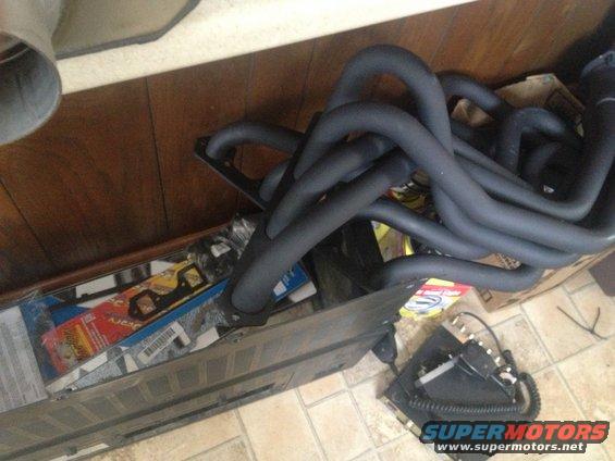 Black exhaust headers in a box with other car parts