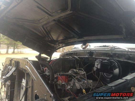 Engine bay of a black vehicle with hood open. Supermotors.net logo visible
