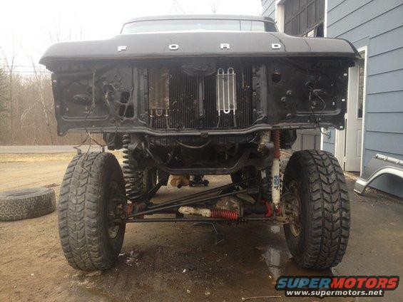 Front of a lifted Ford truck with grille removed, showing radiator and suspension components