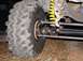 1979 Ford Bronco - Close-up view of a large off-road tire and the vehicle's steering linkage, with a bright yellow coil spring visible.