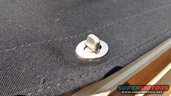 Close-up of a metal snap fastener on black fabric with visible stitching