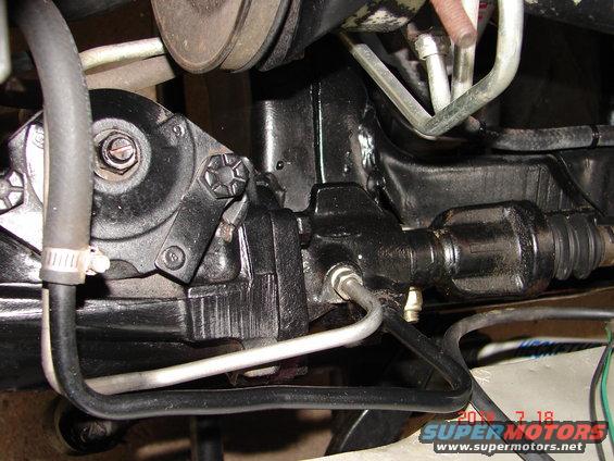 close-up of a black power steering gearbox with hoses and metal lines attached