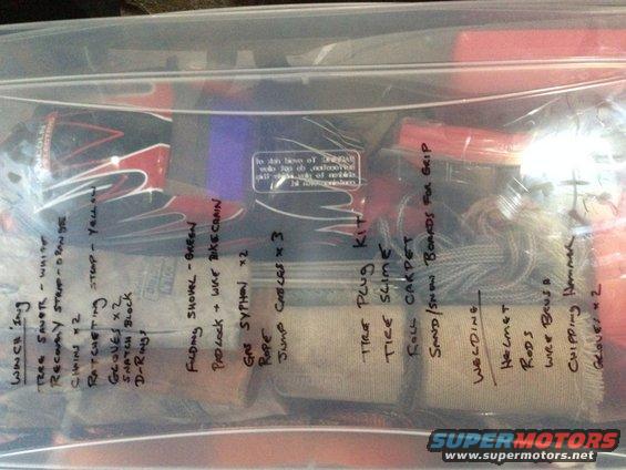 Contents of a plastic bag with handwritten labels including winch, shovel, tire plug kit, and welding gear
