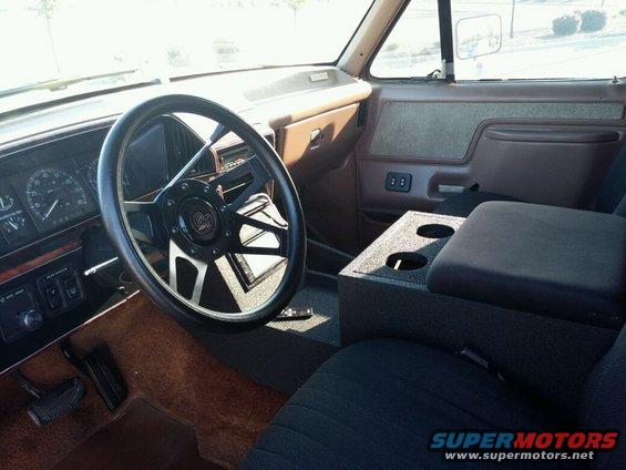 1991 Ford Bronco interior showing aftermarket steering wheel, dashboard, and center console with cup holders