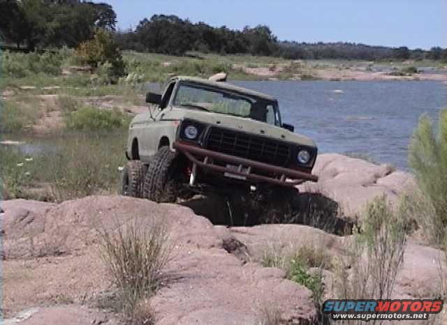 1978 Ford Bronco climbing over rocks by a body of water
