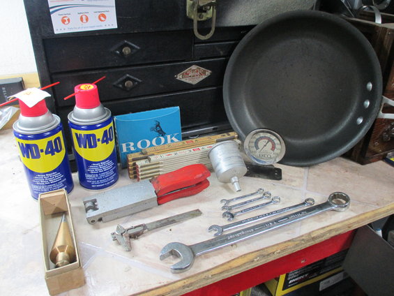 Collection of tools including WD-40 cans, wrenches, a plumb bob, and a frying pan