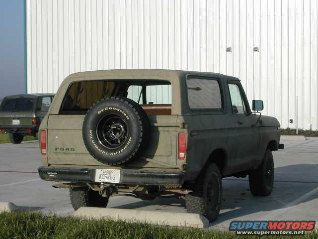 Tan 1978 Ford Bronco with spare tire on rear, parked next to a dark green SUV